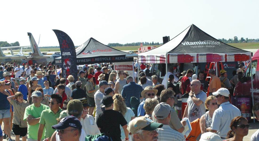Partnership with Wings Over Washington Air Show. Picture shows large crowd at an air show mingling around static displays.